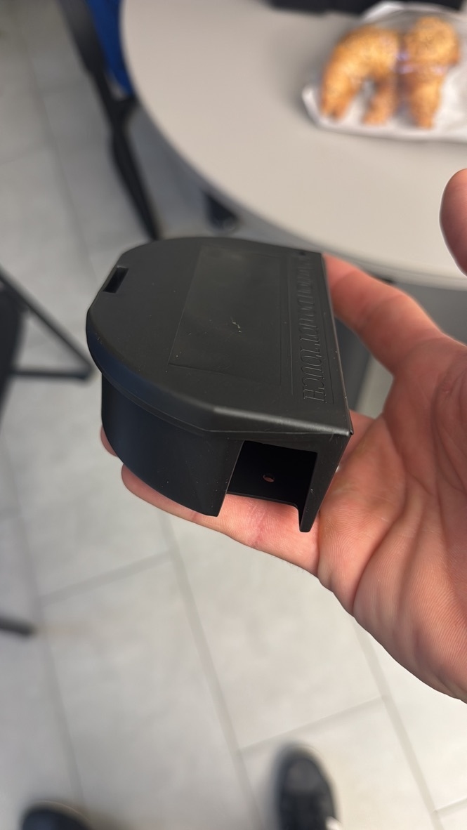 Ein Kammerjaeger haelt in Aesch eine kleine schwarze Kontrolleinheit in der Hand, waehrend im Hintergrund ein Tisch mit Gebaeck zu sehen ist.