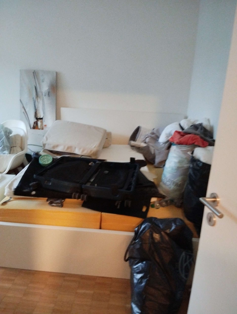 Im Schlafzimmer in Eptingen deutet die Unordnung rund um Bett und Taschen auf moeglichen Bettwanzenbefall hin, weshalb ein Kammerjaeger erforderlich sein kann.