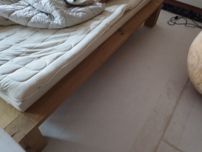 Unter einem Holzbett in Gelterkinden deutet der helle Boden mit leichten Spuren auf moeglichen Befall durch Bettwanzen hin, was den Einsatz eines Kammerjaegers notwendig macht.