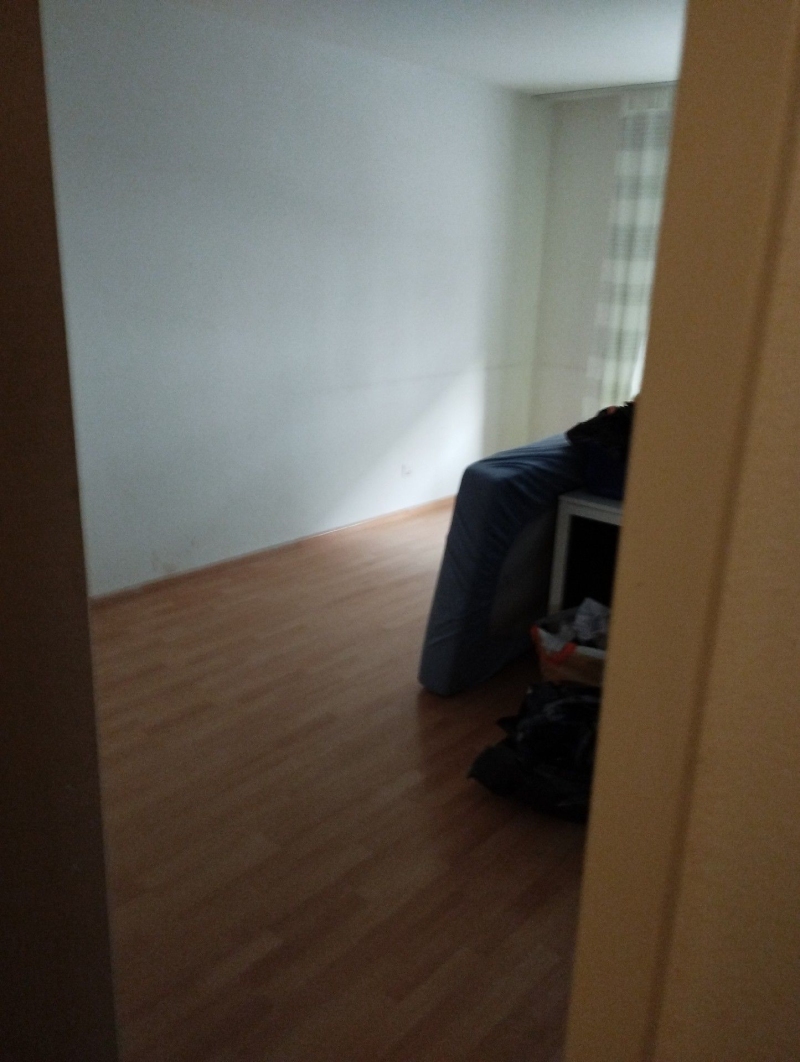 In einem fast leeren Zimmer in Grellingen weist der unordentliche Schlafbereich auf moeglichen Befall hin, was den Einsatz eines Kammerjaegers gegen Bettwanzen noetig macht.