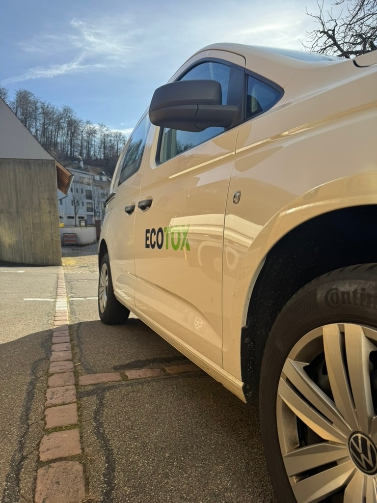Ein Kammerjaegerfahrzeug steht in Aesch seitlich im Sonnenlicht auf einem gepflasterten Parkplatz, waehrend die Umgebung mit Haeusern und Baumbestand im Hintergrund sichtbar ist.