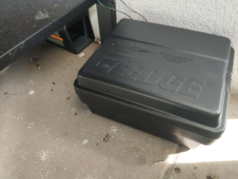 Unter dem Regal deutet die aufgestellte Koederbox in Dittingen auf moegliche Rattenaktivitaet hin, wodurch ein Kammerjaeger im Ort notwendig sein kann.