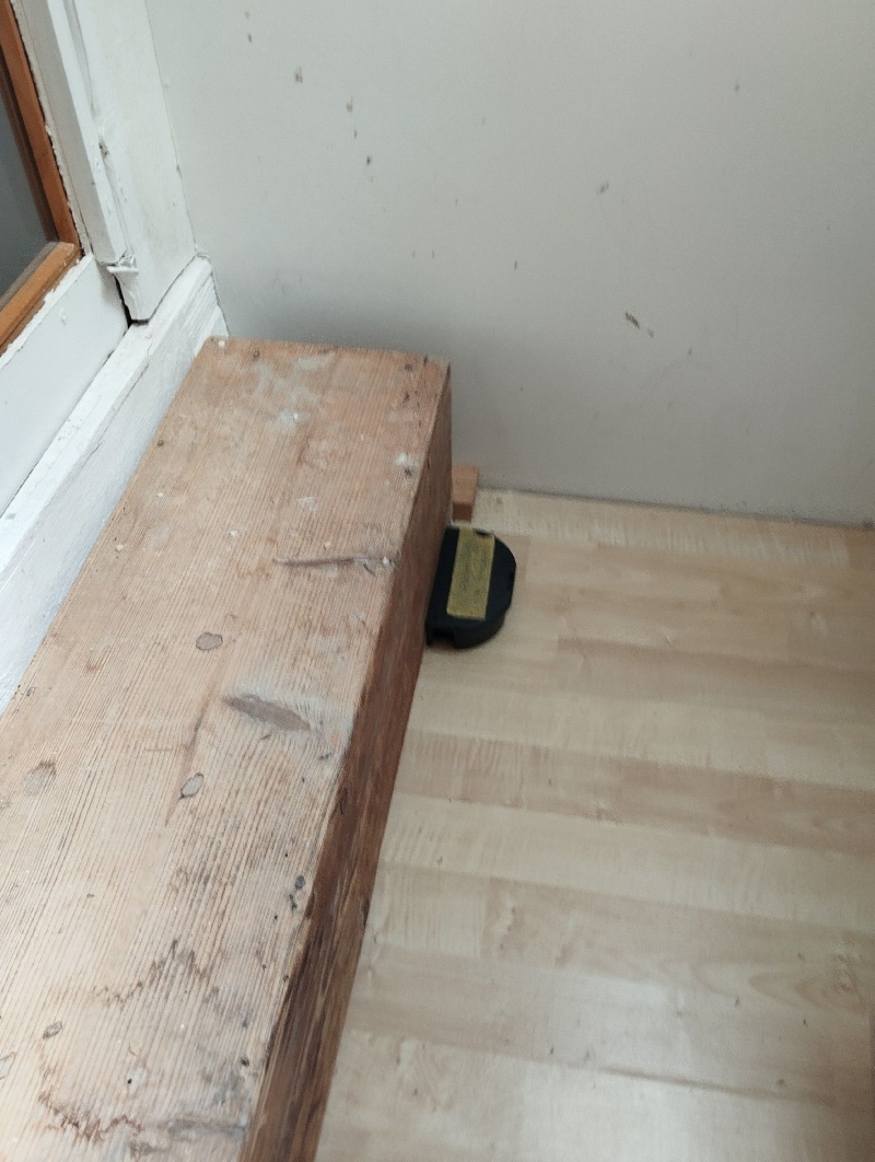 In Haefelfingen weist eine platzierte Falle hinter dem Holztritt auf moegliche Maeuseaktivitaet hin und legt den Einsatz eines Kammerjaeger nahe.