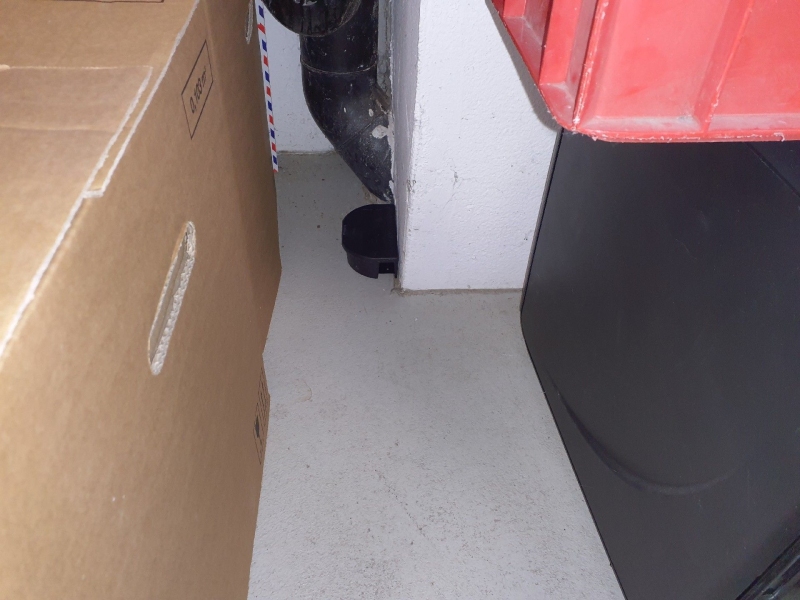 In einem Abstellraum in Kilchberg steht eine Koederbox neben einem Rohr, was auf Maeusebefall hindeutet und den Einsatz eines Kammerjaeger notwendig macht.