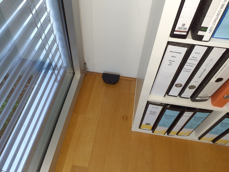 In Lampenberg steht eine schwarze Rattenfalle zwischen Regal und Fenster, was auf einen Einsatz des Kammerjaegers hinweist.