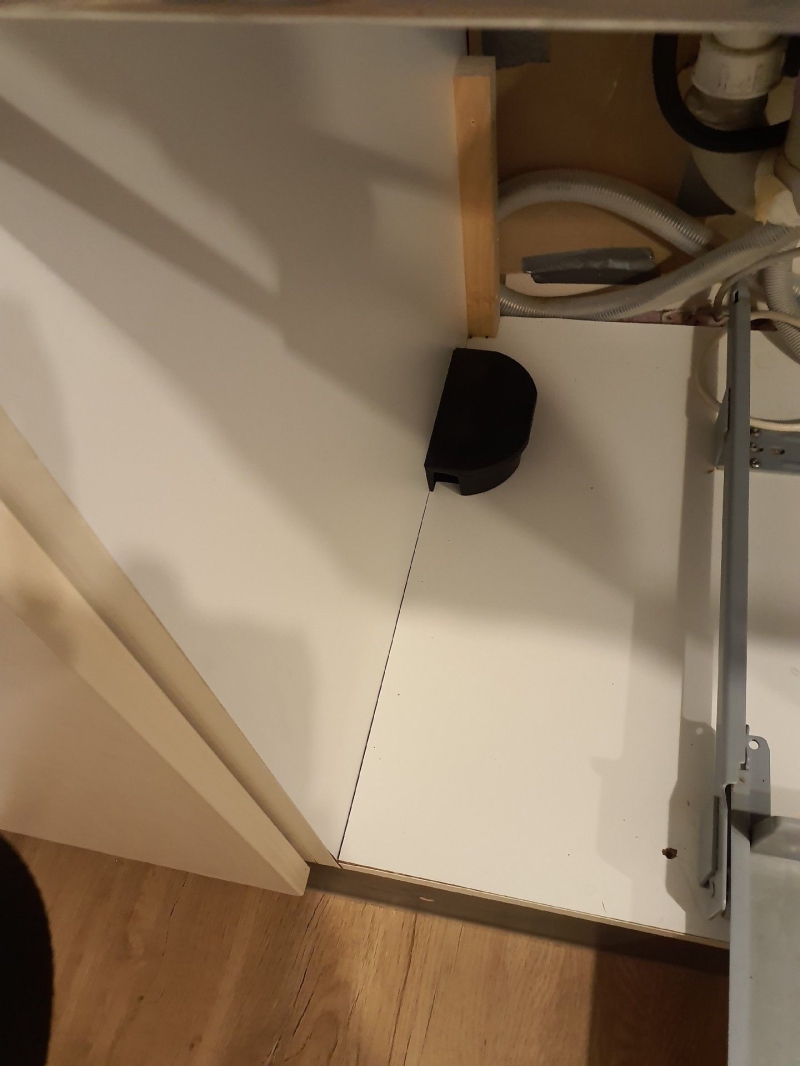 Im Kuechenschrank in Liestal steht eine Rattenfalle neben Leitungen, was auf einen moeglichen Befall hindeutet und den Einsatz eines Kammerjaeger notwendig macht.