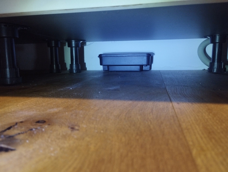 Unter dem Küchenschrank in Reinach steht eine Koederbox auf dem Holzboden, was auf einen moeglichen Maeusebefall hindeutet und den Einsatz eines Kammerjaegers noetig macht.