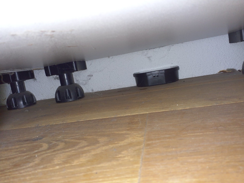 Ein Kammerjaeger platziert in Aesch eine Maeusekoederbox unter einem tiefen Moebelstück, wo Spuren und Staub auf regelmaessige Aktivitaet hindeuten.