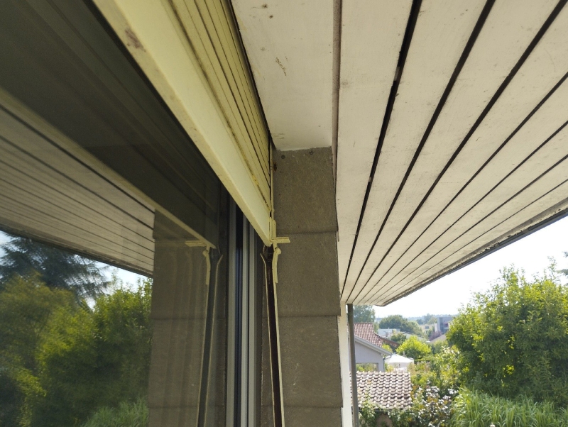 Unter dem Dachvorsprung eines Hauses in Binningen deutet eine geschuetzte Ecke auf ein moegliches Hornissennest hin, das einen Kammerjaeger erfordern koennte.