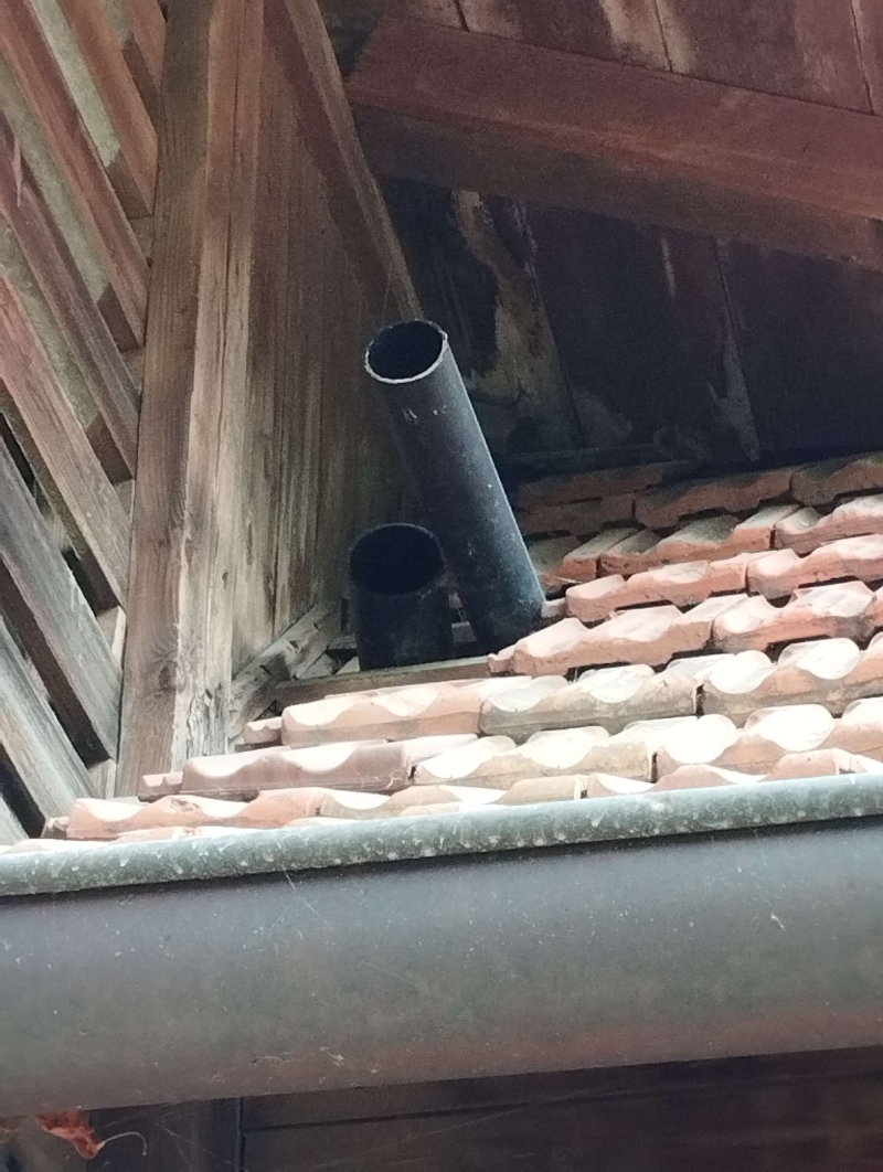 Unter dem verwitterten Dachbereich in Rickenbach deutet das geoeffnete Rohr auf ein moegliches Hornissennest hin, was den Einsatz eines Kammerjaegers im Ort erforderlich macht.