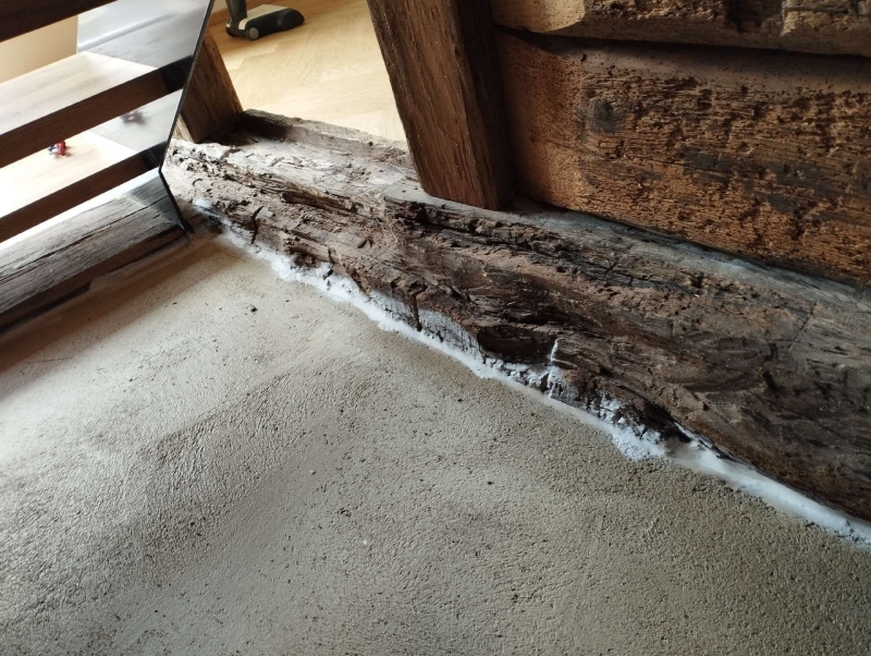 Entlang eines alten Holztraegers in Diegten deutet weisses Pulver auf moegliche Ameisenaktivitaet hin, was den Einsatz eines Kammerjaegers erforderlich macht.